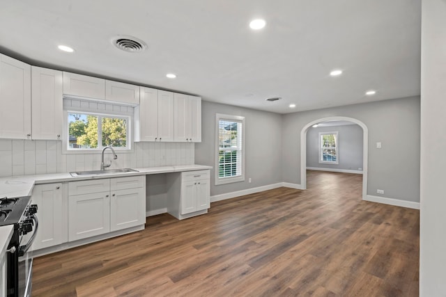 kitchen featuring visible vents, dark wood-type flooring, a sink, backsplash, and gas range oven