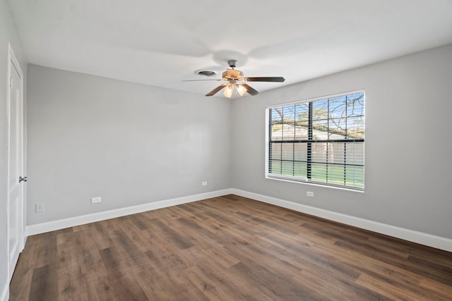 spare room with visible vents, baseboards, dark wood-style floors, and a ceiling fan