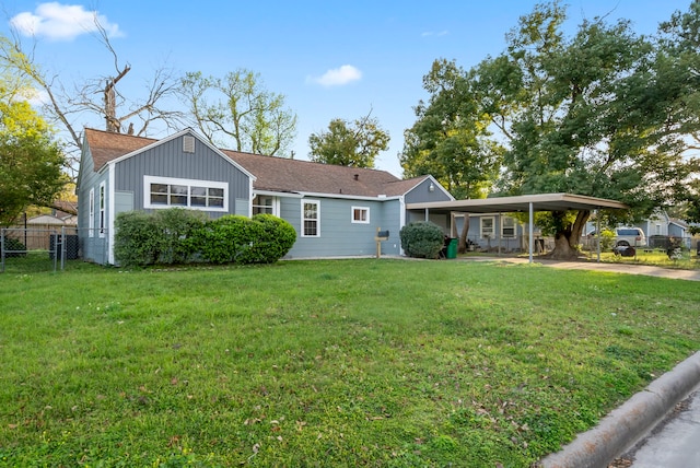 ranch-style house featuring a front yard, fence, roof with shingles, a carport, and concrete driveway