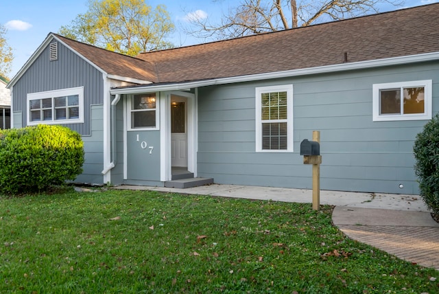 view of front facade featuring a front yard and a shingled roof