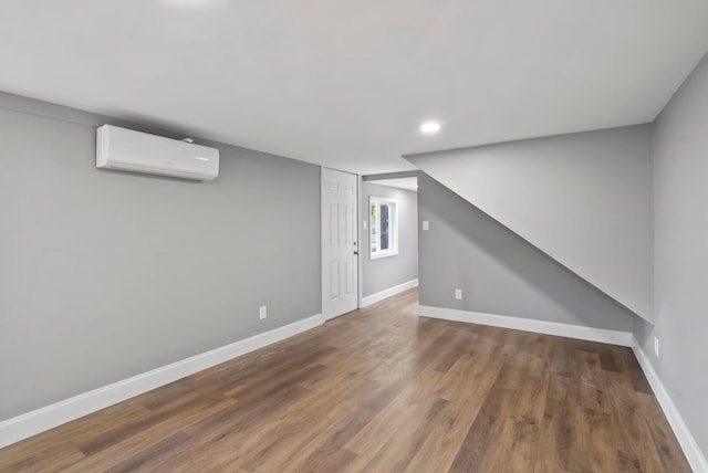 basement with recessed lighting, a wall mounted AC, baseboards, and wood finished floors