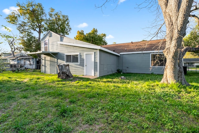 rear view of house featuring a lawn and fence