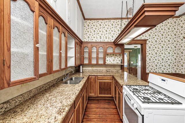 406 7th St, Sealy, TX 77474 - kitchen with brown cabinets, a sink, wallpapered walls, and gas range gas stove