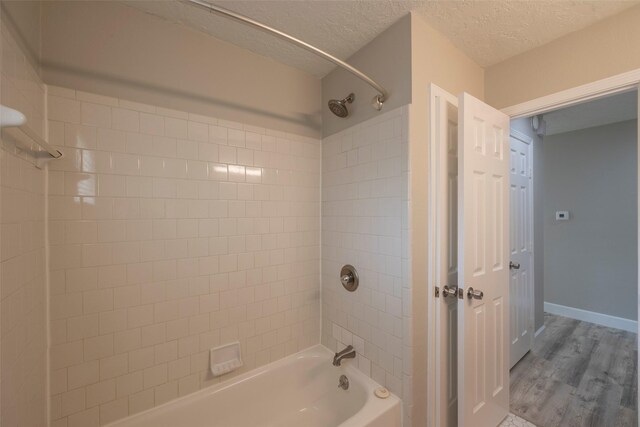 9315 Fairdale Ln, Houston, TX 77063 - bathroom with bathing tub / shower combination, wood finished floors, a textured ceiling, and baseboards