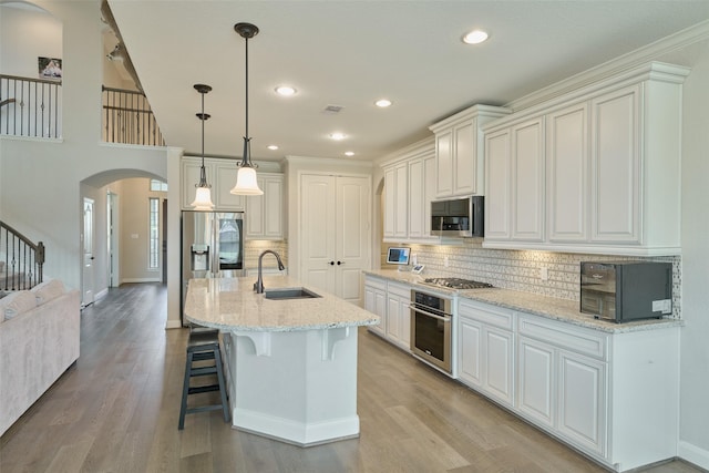 120 Shane St, Montgomery, TX 77316 - kitchen with stainless steel appliances, a sink, arched walkways, baseboards, and light wood-type flooring