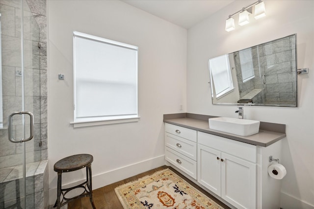 bathroom with a stall shower, wood finished floors, vanity, and baseboards