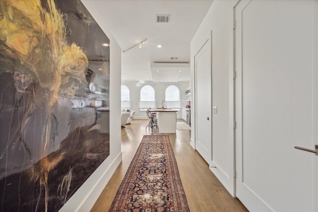 hall with recessed lighting, visible vents, a sink, and wood finished floors