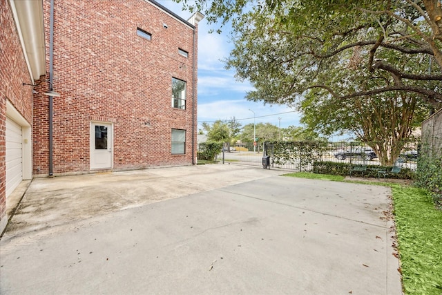 view of property exterior featuring brick siding and a gate