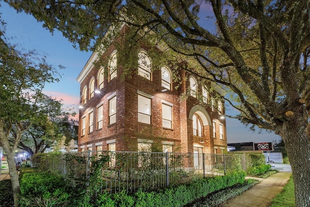 property at dusk with a fenced front yard