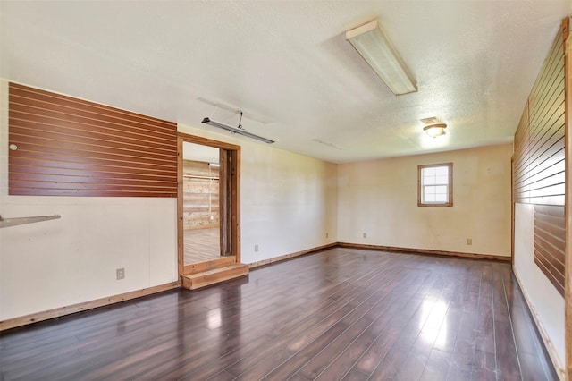 empty room featuring baseboards, wood finished floors, and a textured ceiling