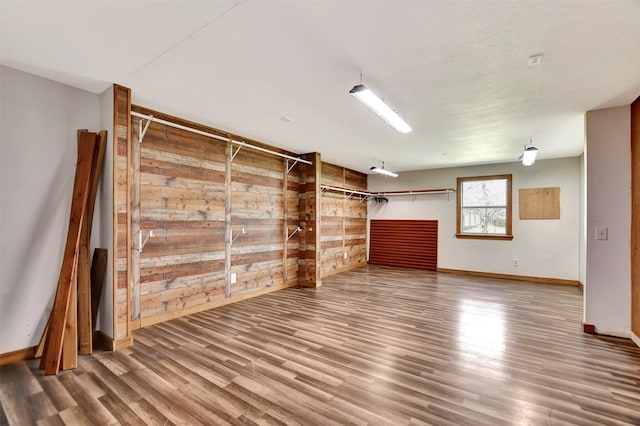 basement featuring wooden walls, wood finished floors, and baseboards