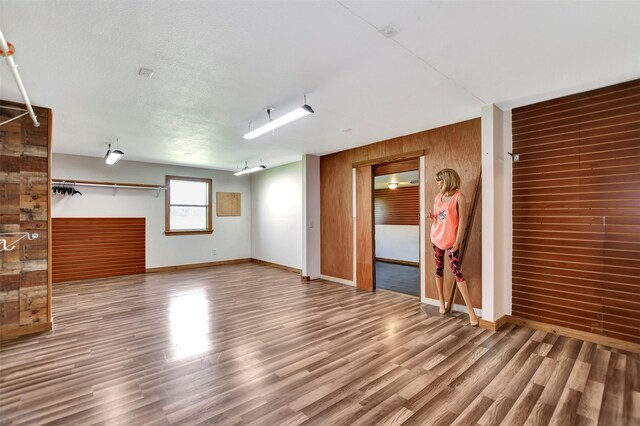 interior space with baseboards, wooden walls, and wood finished floors