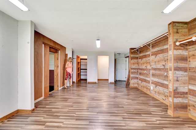 interior space with baseboards, wood finished floors, and wooden walls