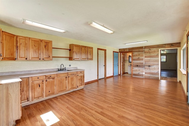kitchen with a sink, light wood-type flooring, baseboards, open shelves, and light countertops