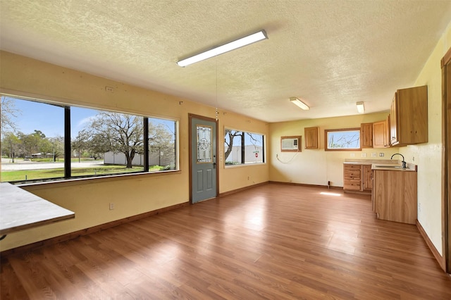 unfurnished living room with baseboards, wood finished floors, a textured ceiling, and a sink