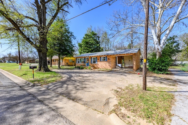 view of front facade with aphalt driveway, metal roof, and a front yard