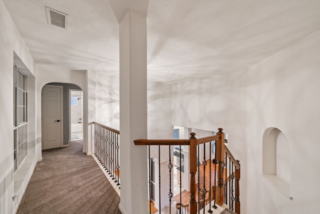 6307 Shoreview Ct, Humble, TX 77346 - hallway featuring an upstairs landing, a textured ceiling, carpet floors, arched walkways, and visible vents
