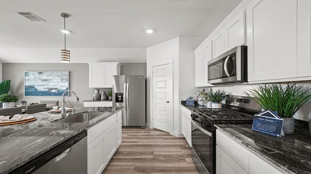 13913 Bahia Bay, Texas City, TX 77591 - kitchen featuring appliances with stainless steel finishes, a sink, light wood-style flooring, white cabinetry, and dark stone countertops