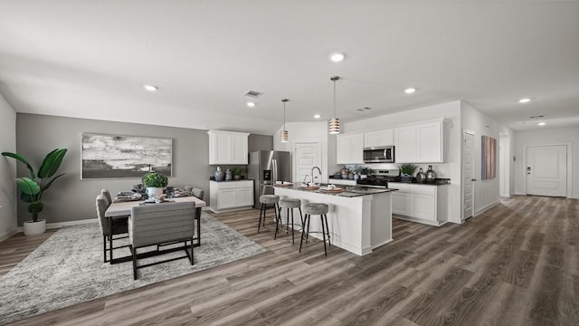 13913 Bahia Bay, Texas City, TX 77591 - kitchen with stainless steel appliances, a kitchen island with sink, wood finished floors, white cabinets, and recessed lighting