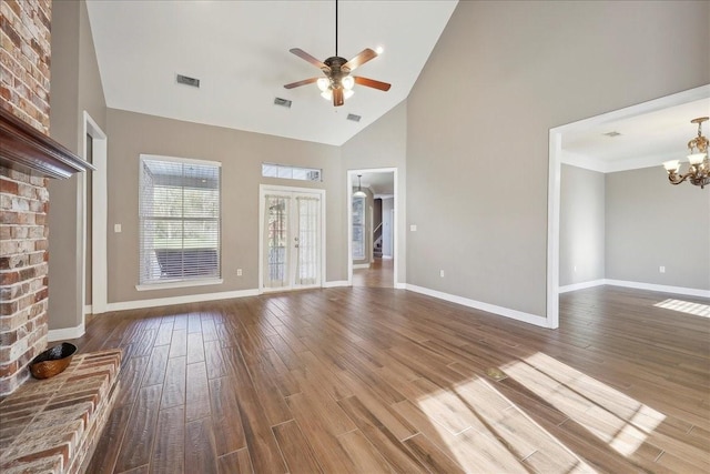 7403 S Park Rd, Lumberton, TX 77657 - unfurnished living room featuring visible vents, high vaulted ceiling, ceiling fan with notable chandelier, wood finished floors, and baseboards