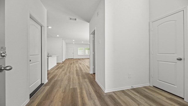 corridor featuring wood finished floors, baseboards, visible vents, and recessed lighting