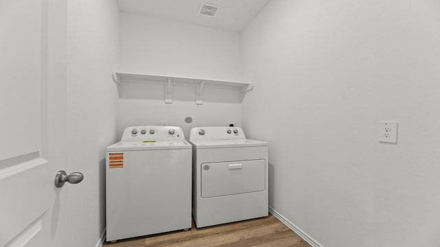 laundry area featuring visible vents, baseboards, light wood-style floors, laundry area, and washer and clothes dryer