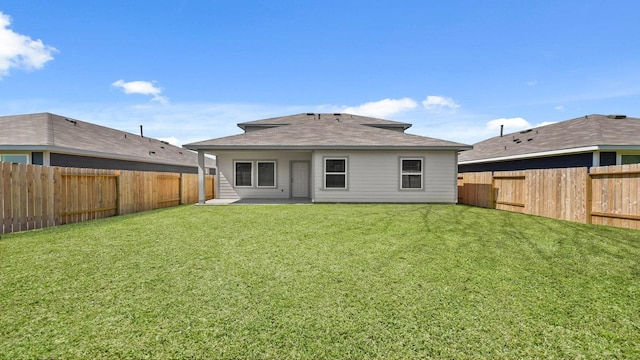 rear view of house featuring a yard and a fenced backyard