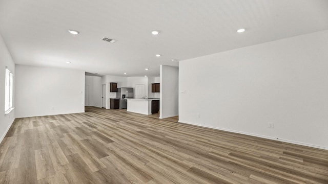 unfurnished living room featuring light wood-type flooring, baseboards, visible vents, and recessed lighting
