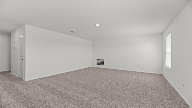 empty room with carpet, visible vents, and baseboards