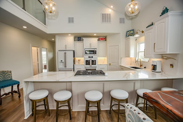 kitchen featuring a sink, stainless steel appliances, visible vents, and a peninsula