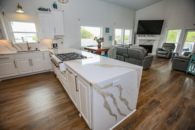 kitchen with a sink, dark wood-type flooring, a peninsula, and a healthy amount of sunlight