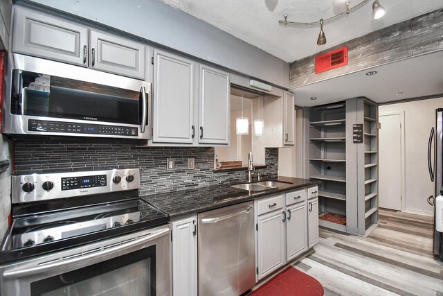 11525 Burdine St Unit 421, Houston, TX 77035 - kitchen with light wood-style flooring, a sink, backsplash, stainless steel appliances, and dark stone counters