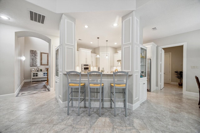 4106 Tee Tree Ct, Spring, TX 77386 - kitchen with stainless steel appliances, white cabinetry, a kitchen bar, baseboards, and recessed lighting