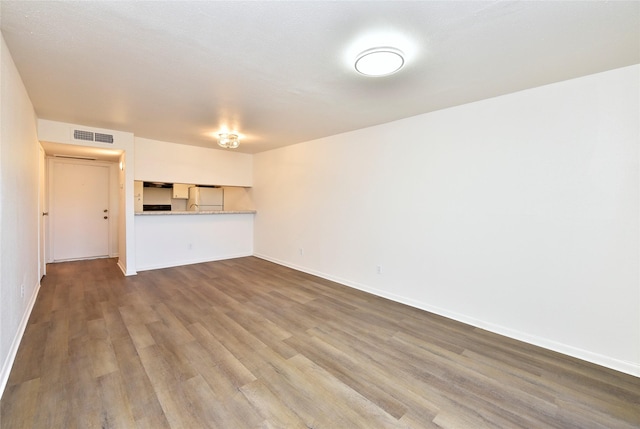 unfurnished living room with dark wood-style flooring and baseboards