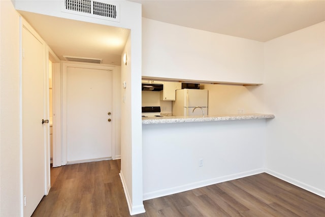 kitchen with freestanding refrigerator, under cabinet range hood, wood finished floors, and light countertops