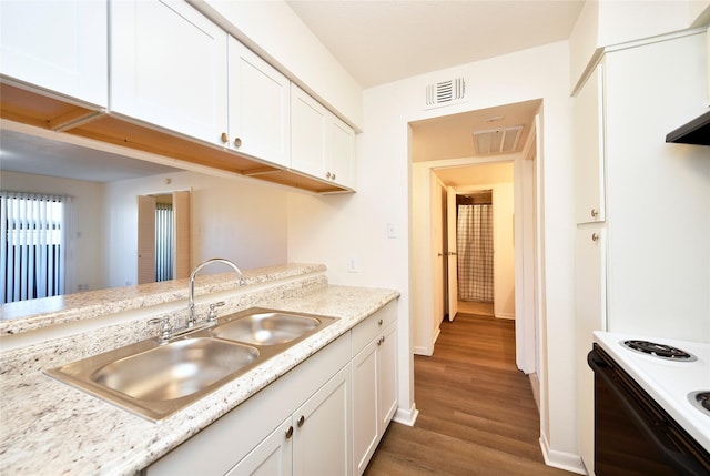 kitchen featuring a sink, electric range oven, white cabinets, wood finished floors, and baseboards