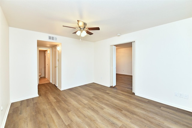 spare room featuring a ceiling fan, light wood-style floors, and baseboards