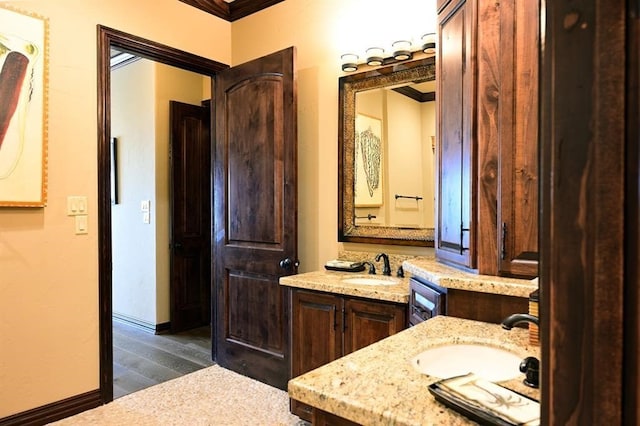 bathroom with a sink, baseboards, two vanities, and wood finished floors