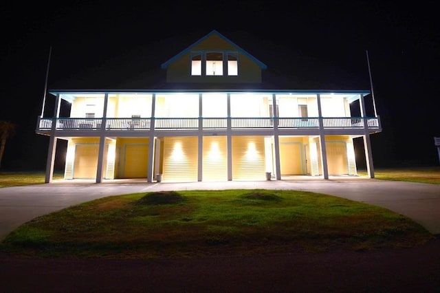 view of front of property featuring a balcony, a lawn, and curved driveway
