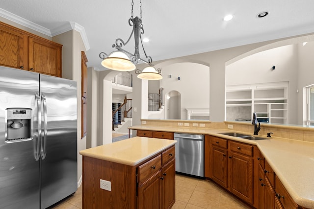 kitchen with light tile patterned flooring, a sink, appliances with stainless steel finishes, arched walkways, and ornamental molding