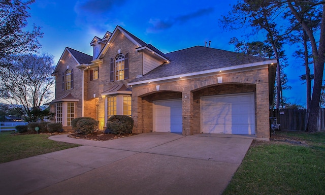 view of front of house with brick siding, driveway, fence, and an attached garage