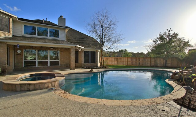 view of swimming pool with a pool with connected hot tub, fence, and a patio