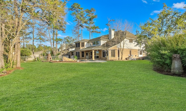 back of property featuring a chimney, a patio, fence, and a lawn