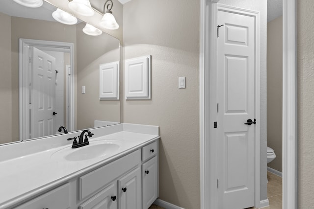 bathroom featuring baseboards, toilet, and vanity