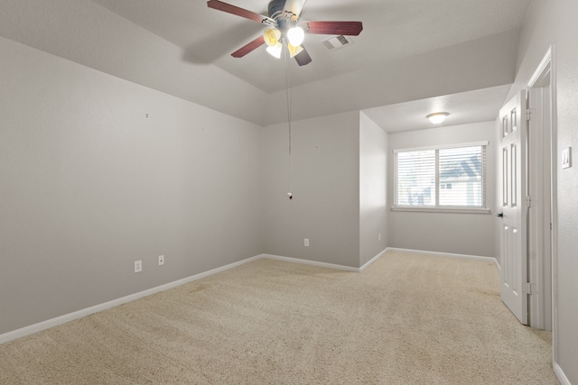 empty room with lofted ceiling, light colored carpet, baseboards, visible vents, and a ceiling fan