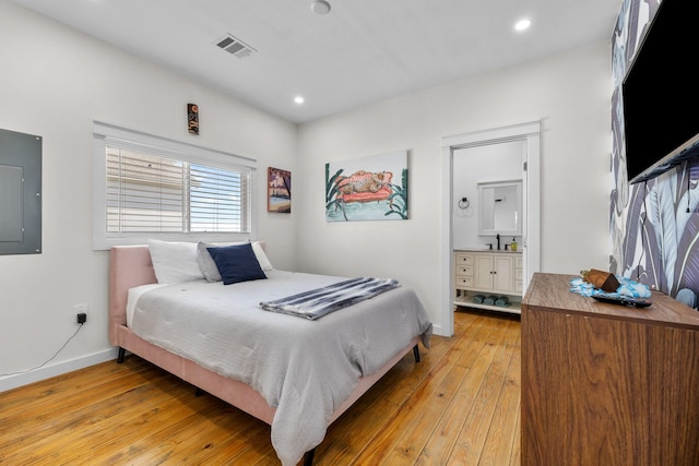 1072 Johnson Rd, Gilchrist, TX 77617 - bedroom with light wood-style flooring, electric panel, recessed lighting, baseboards, and ensuite bath