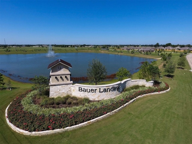 community sign featuring a lawn and a water view