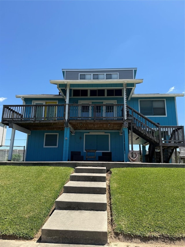 34 N Omega St, Galveston, TX 77568 - rear view of house featuring stairs, a yard, a deck, and board and batten siding