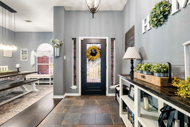 entryway with stone finish flooring, baseboards, visible vents, and a towering ceiling