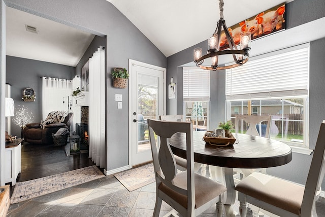 dining area with visible vents, a chandelier, lofted ceiling, baseboards, and stone tile flooring